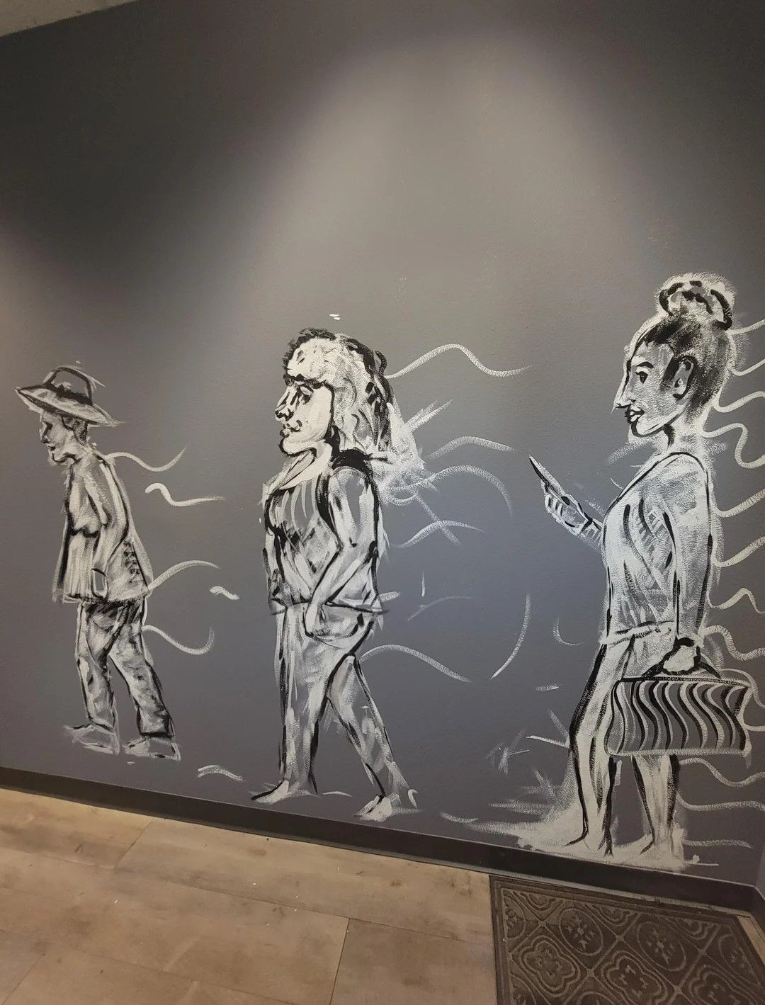 Painting on a wall of women of different ages walking 