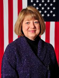 Portrait of a woman in a purple jacket before an American flag backdrop