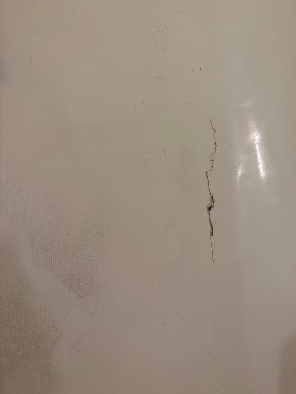 A long, dark crack on a white surface, possibly a bathtub or wall.