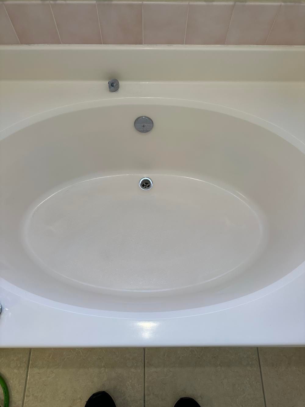 Oval white bathtub with three chrome fixtures.
