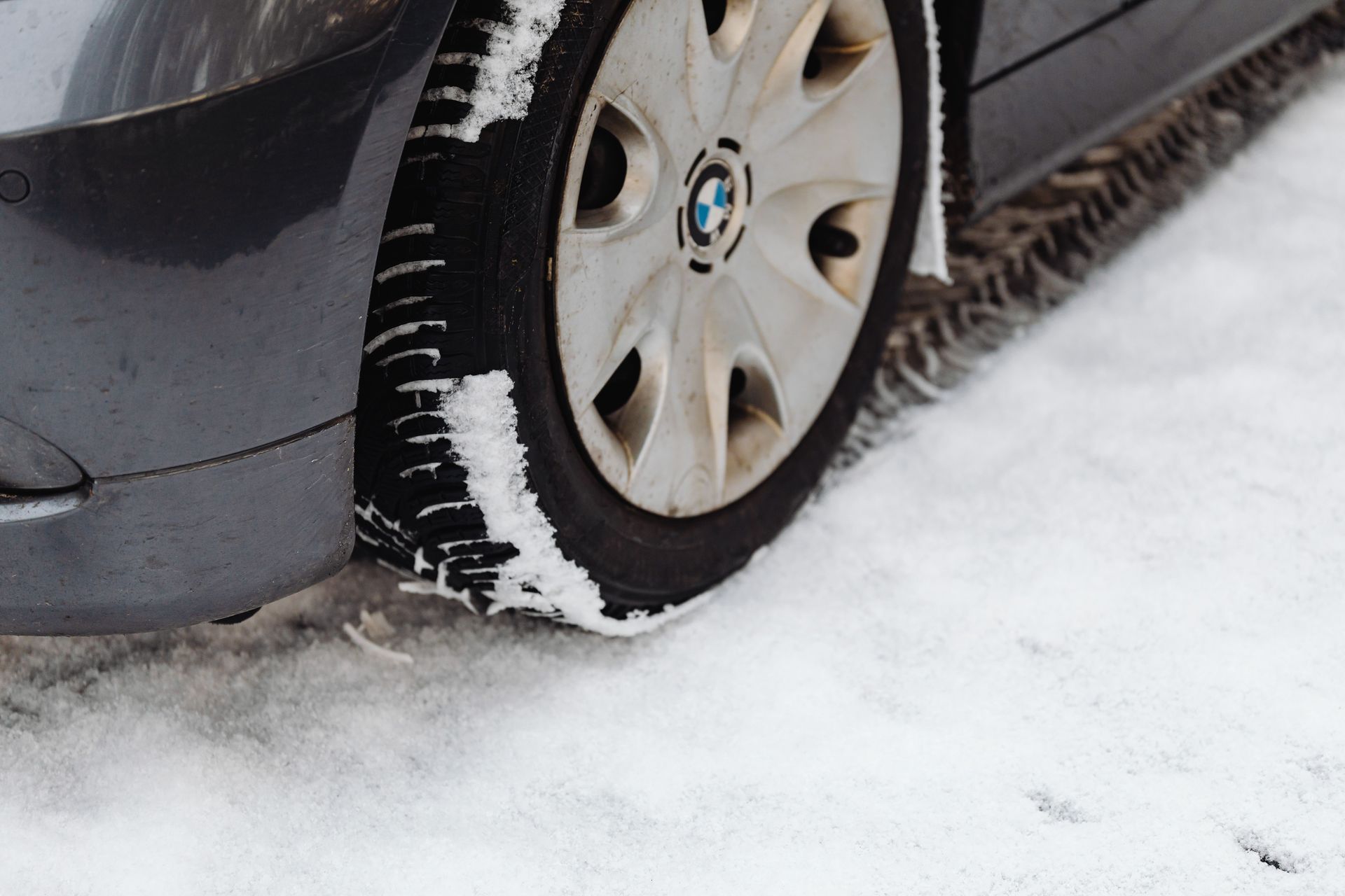 Car tire driving through the snow with snow sticking to the tire tread