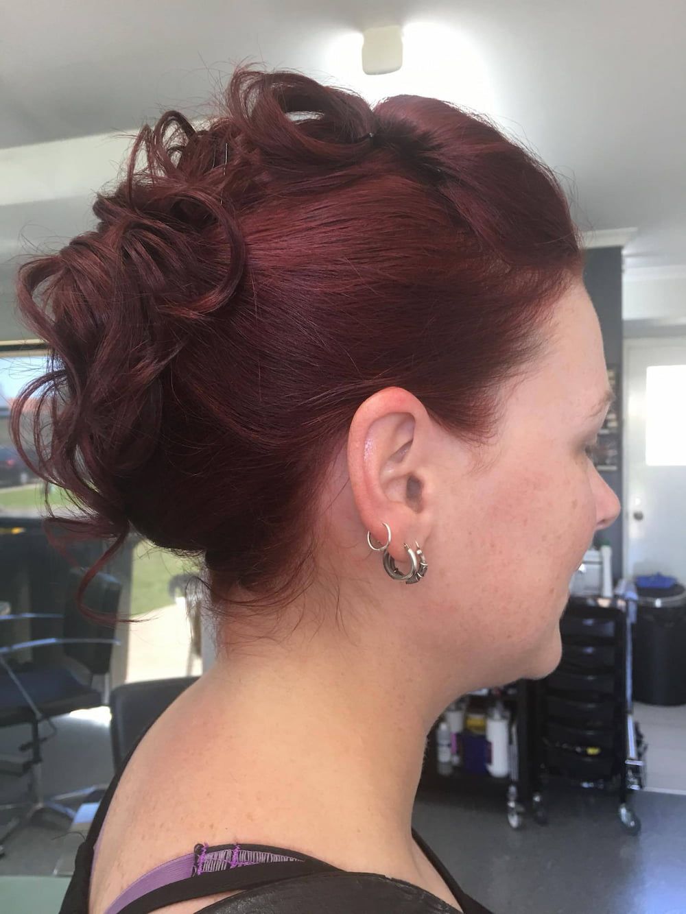 A Woman With Red Hair is Wearing Earrings and Has Her Hair in a Bun — Rayzr Hair Artistry in Eli Waters, QLD