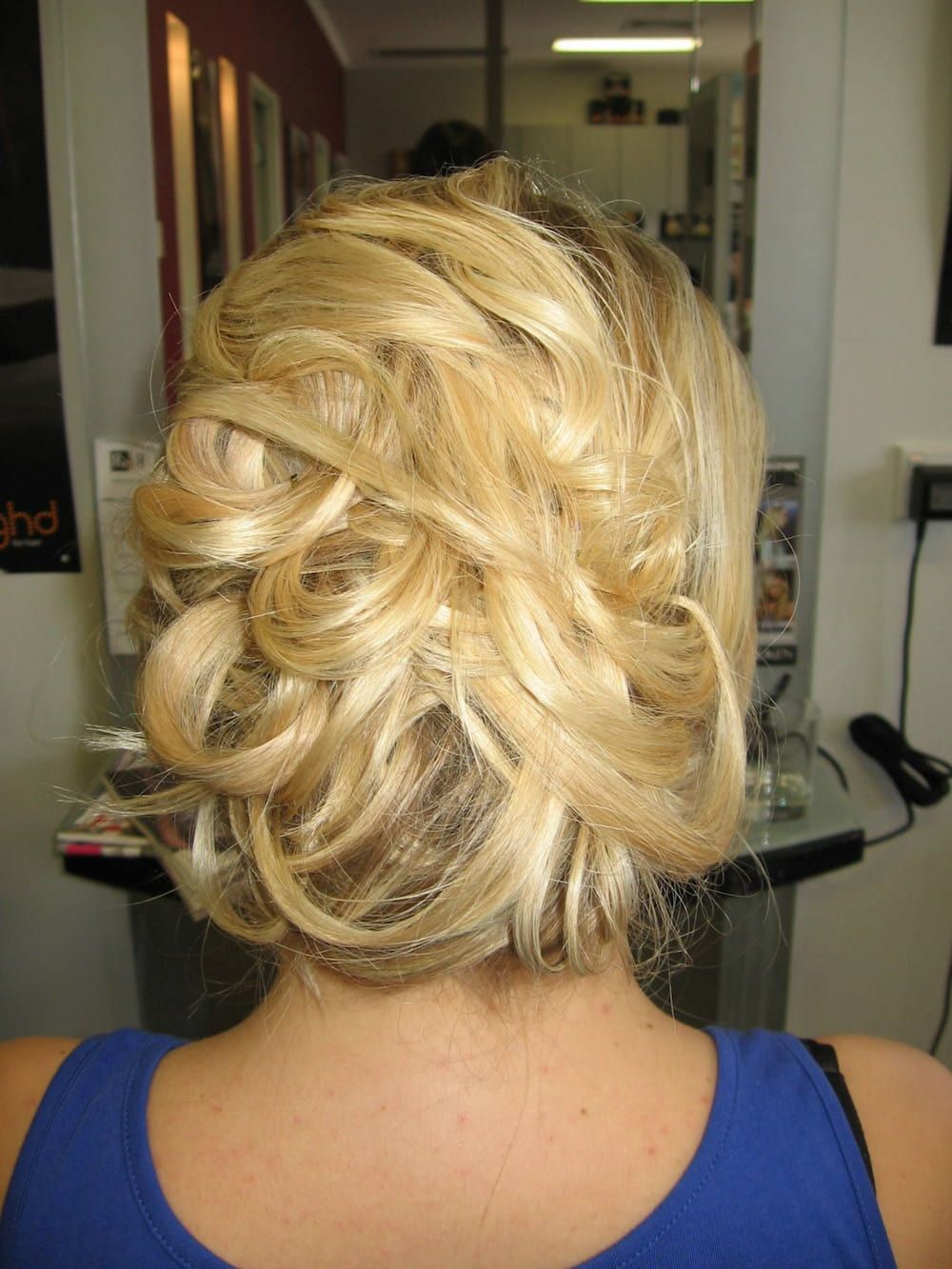 A Woman With Blonde Hair in a Messy Bun is Wearing a Blue Tank Top — Rayzr Hair Artistry in Eli Waters, QLD