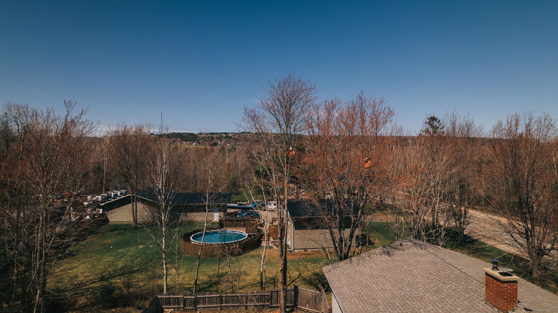 An aerial view of a house with a pool in the backyard surrounded by trees.