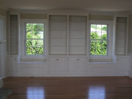 An empty living room with lots of shelves and windows