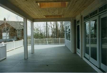 A large deck with a white railing and sliding glass doors