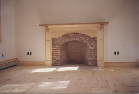 An empty room with a fireplace and a wooden floor