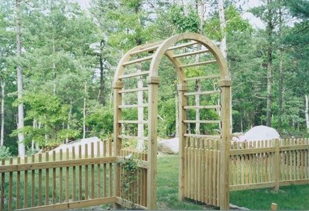 A wooden archway with a fence in the background