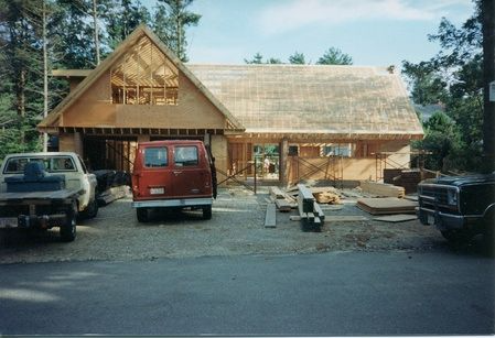 A red van is parked in front of a house under construction