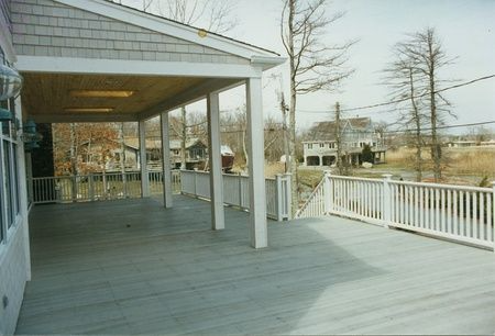 A large deck with a white railing overlooking a river
