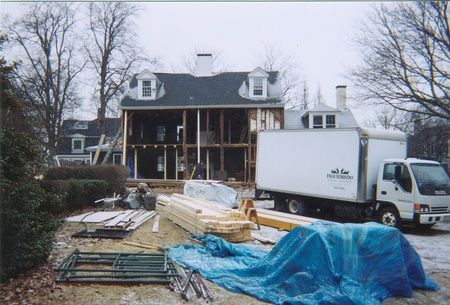 A white truck with the word moving on it is parked in front of a house under construction