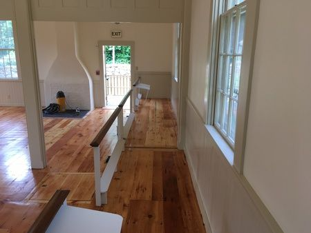 A hallway in a house with wooden floors and a sign that says exit