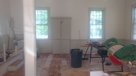 A room with a lot of windows and a trash can in it.