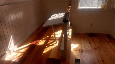 A room with a wooden floor and a table in front of a window.