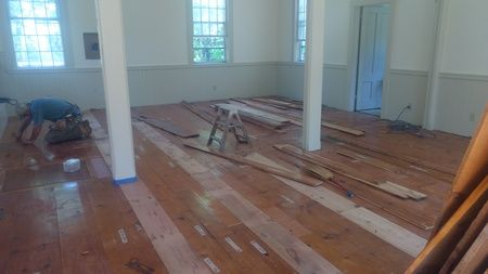 A man is working on a wooden floor in a room.