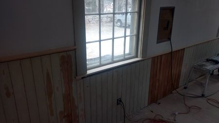 A room with wood paneling on the walls and a window.