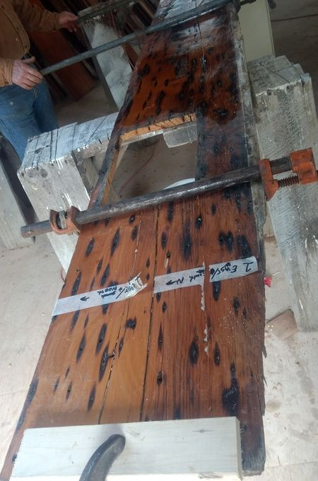 A person is working on a wooden table with a clamp.