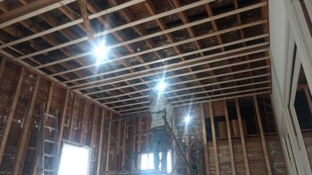 A man is standing on a ladder in a room with a wooden ceiling.