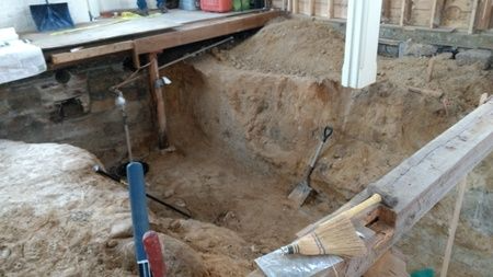 A pile of dirt is sitting on the ground next to a wooden beam.