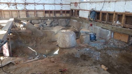 A large rock is sitting in the middle of a construction site.
