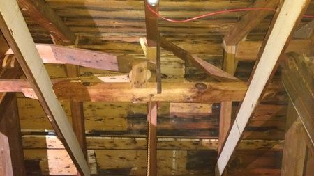 A ceiling with a lot of wooden beams and wires hanging from it.