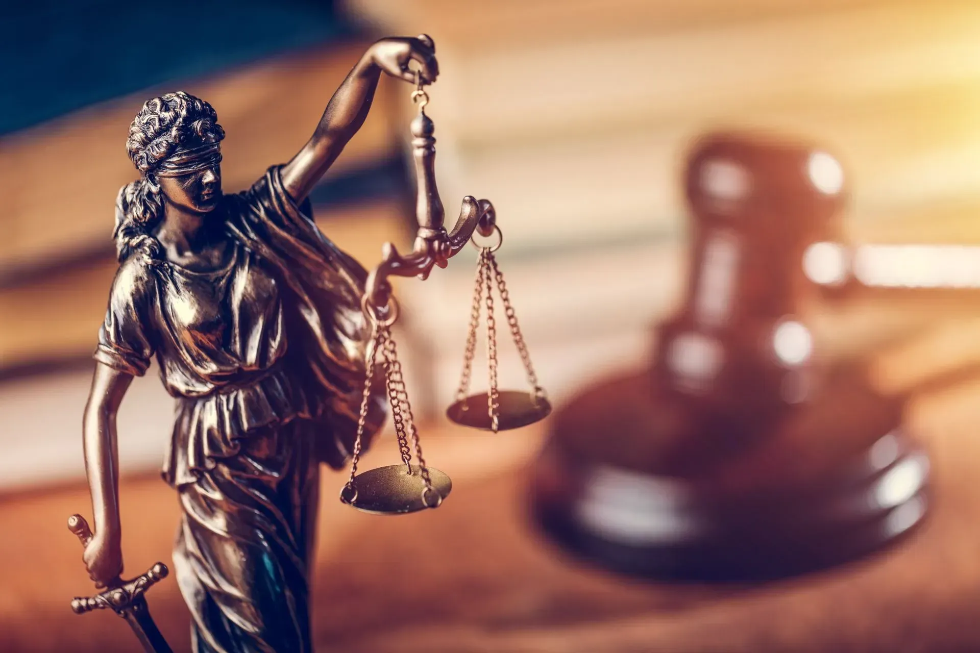 Lady Justice statue with scales in front of a wooden judge’s gavel