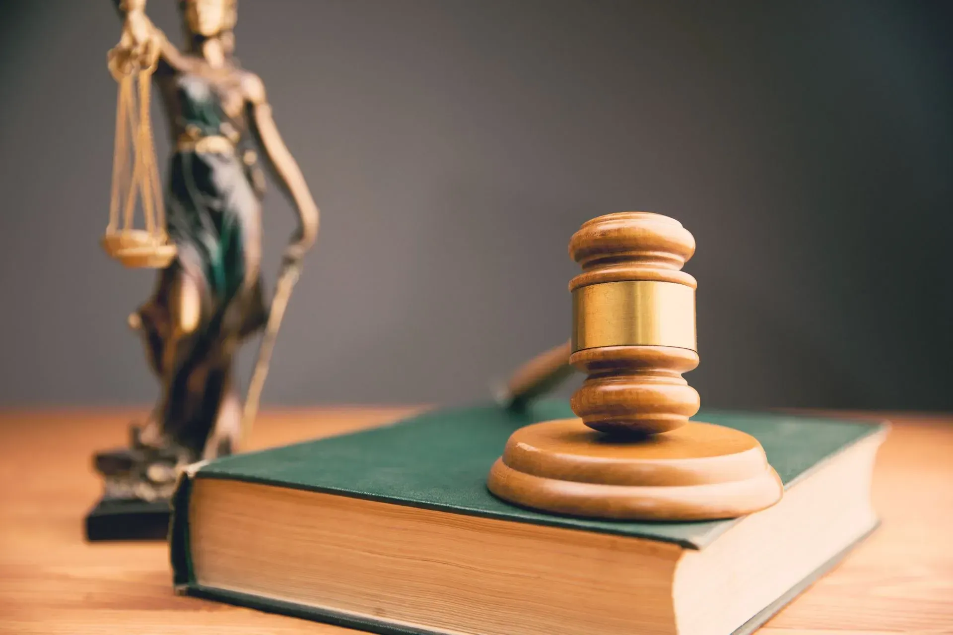 Law book with judge’s gavel and scales of justice in a courtroom setting