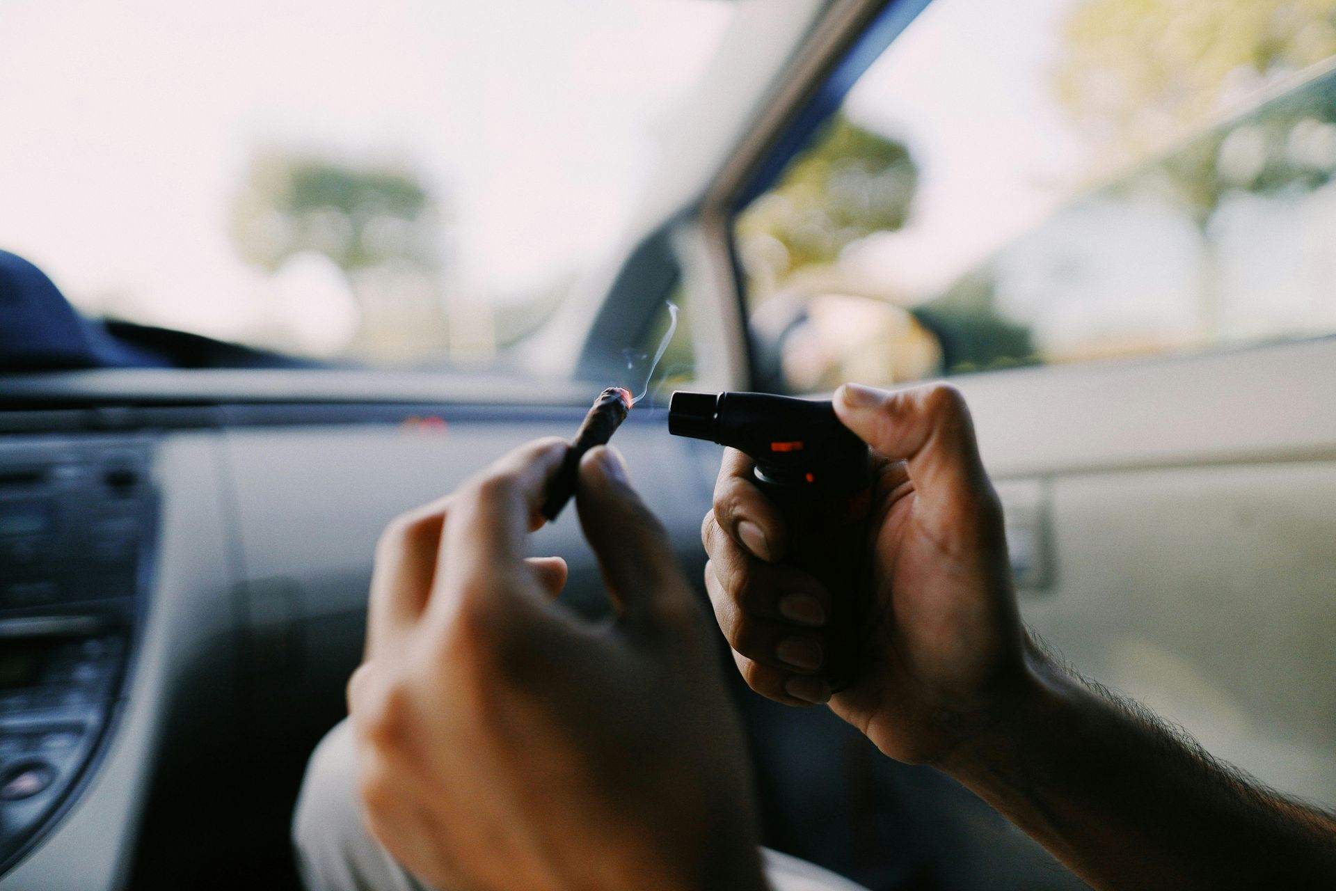 Hands holding a small device inside a car, with a blurred road visible through the window.
