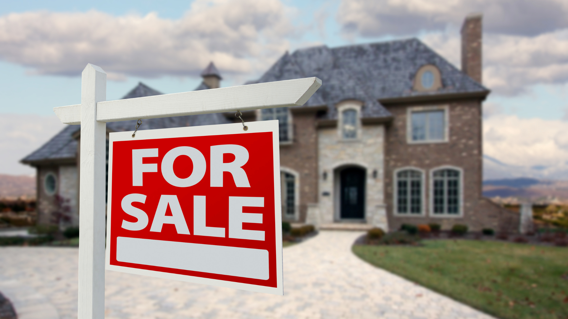 A for sale sign is in front of a large house.