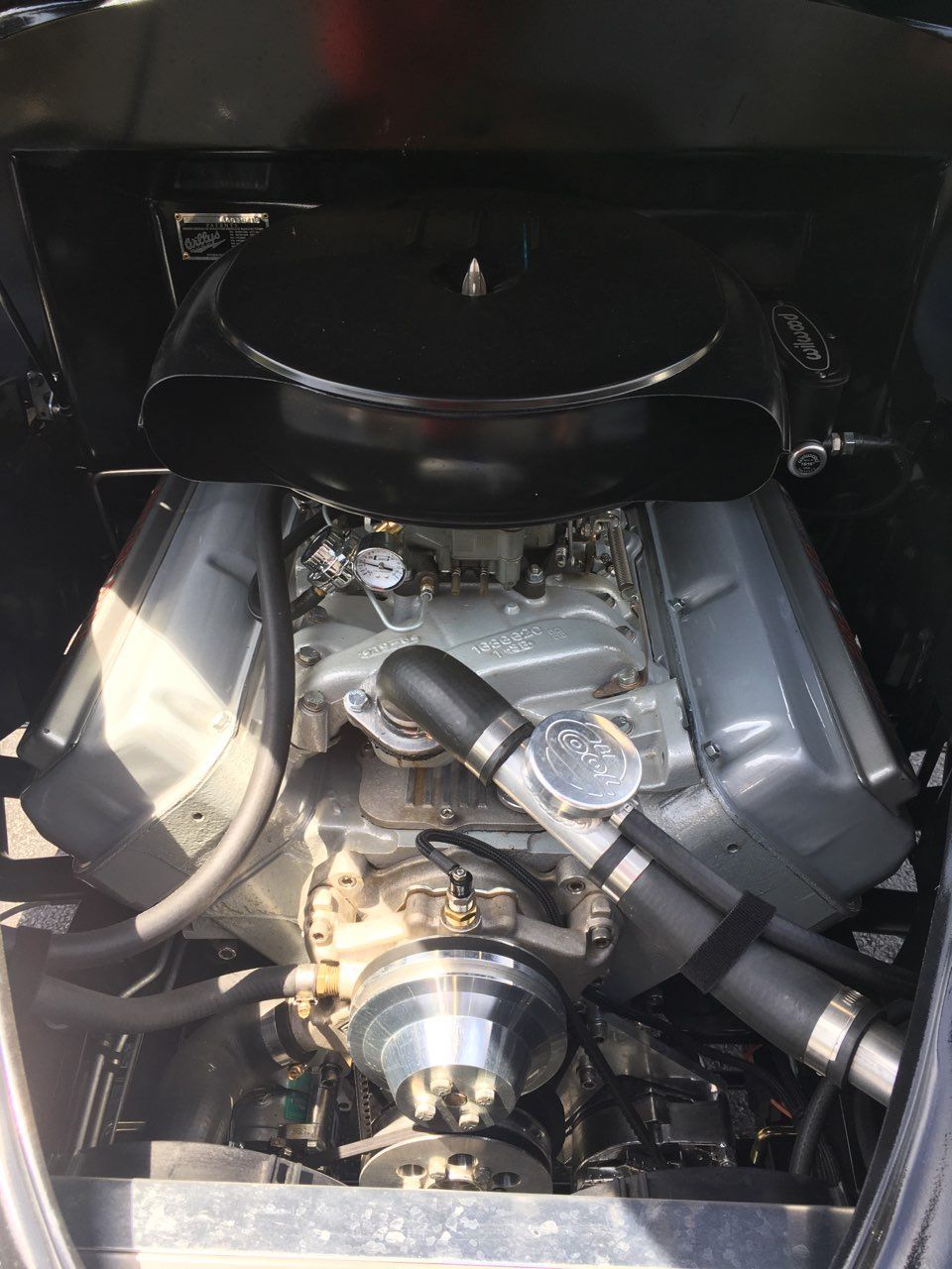 Car engine bay with large V8 motor, chrome air cleaner, and polished intake components.
