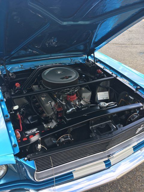 Open blue car hood revealing a detailed engine bay with a round air cleaner.