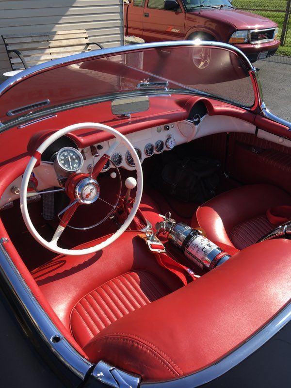 Red interior of a classic convertible car with white steering wheel and red seats.