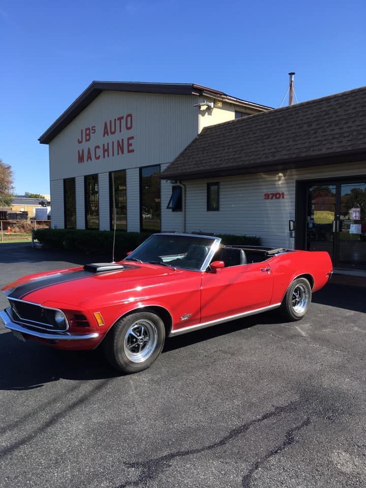 Red convertible muscle car parked in front of a J & B Auto Machine shop building.