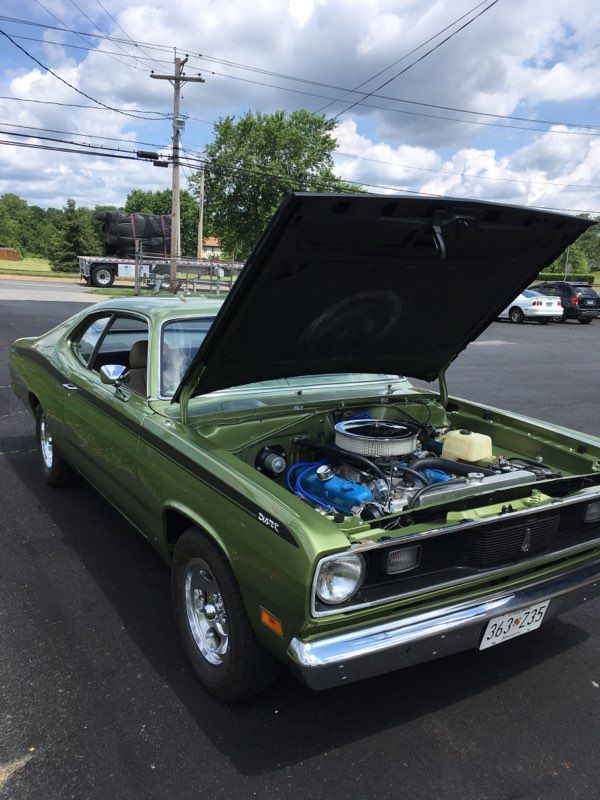 Green Plymouth Duster with hood open, parked outside on a sunny day.