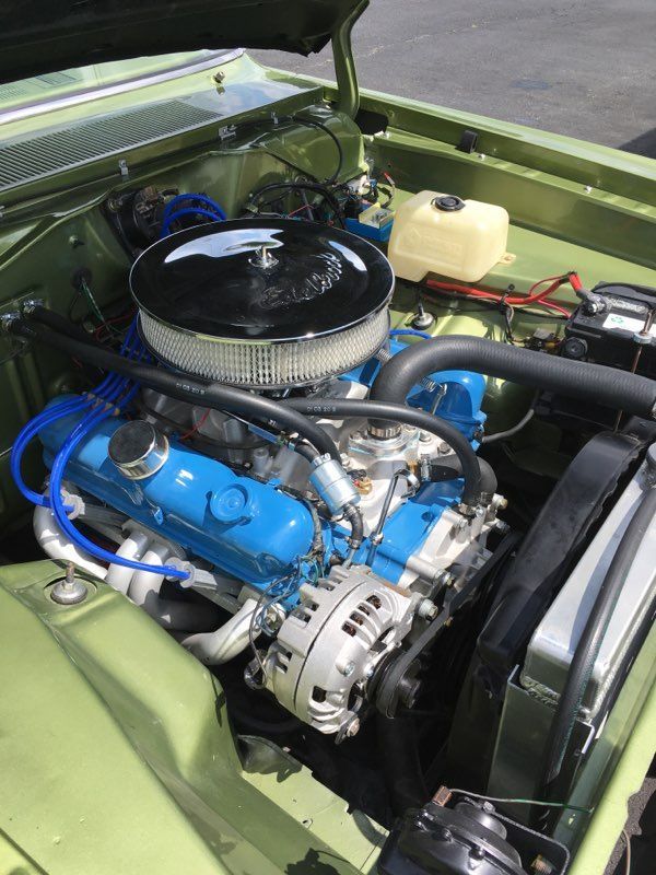 Green car engine bay with a blue engine, chrome air cleaner, and white alternator.