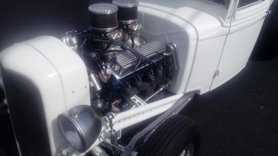 White hot rod with a powerful engine, chrome accents, and a bright, sunny setting.
