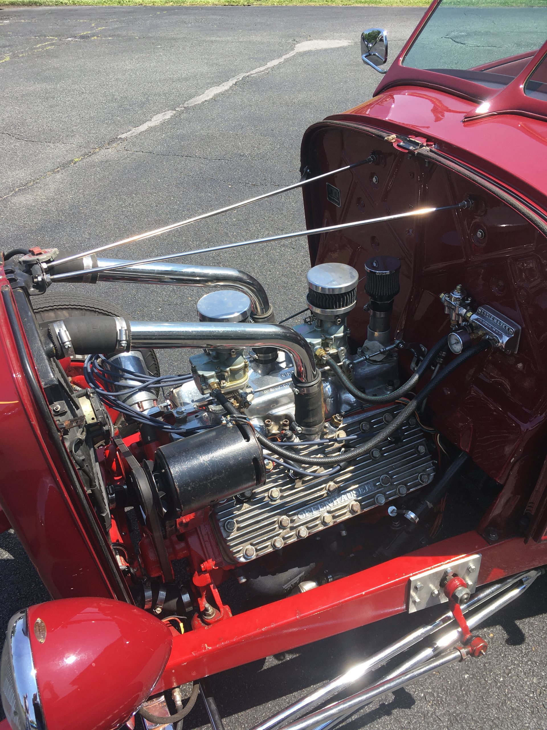 Red classic hot rod car engine compartment, chrome and black details.