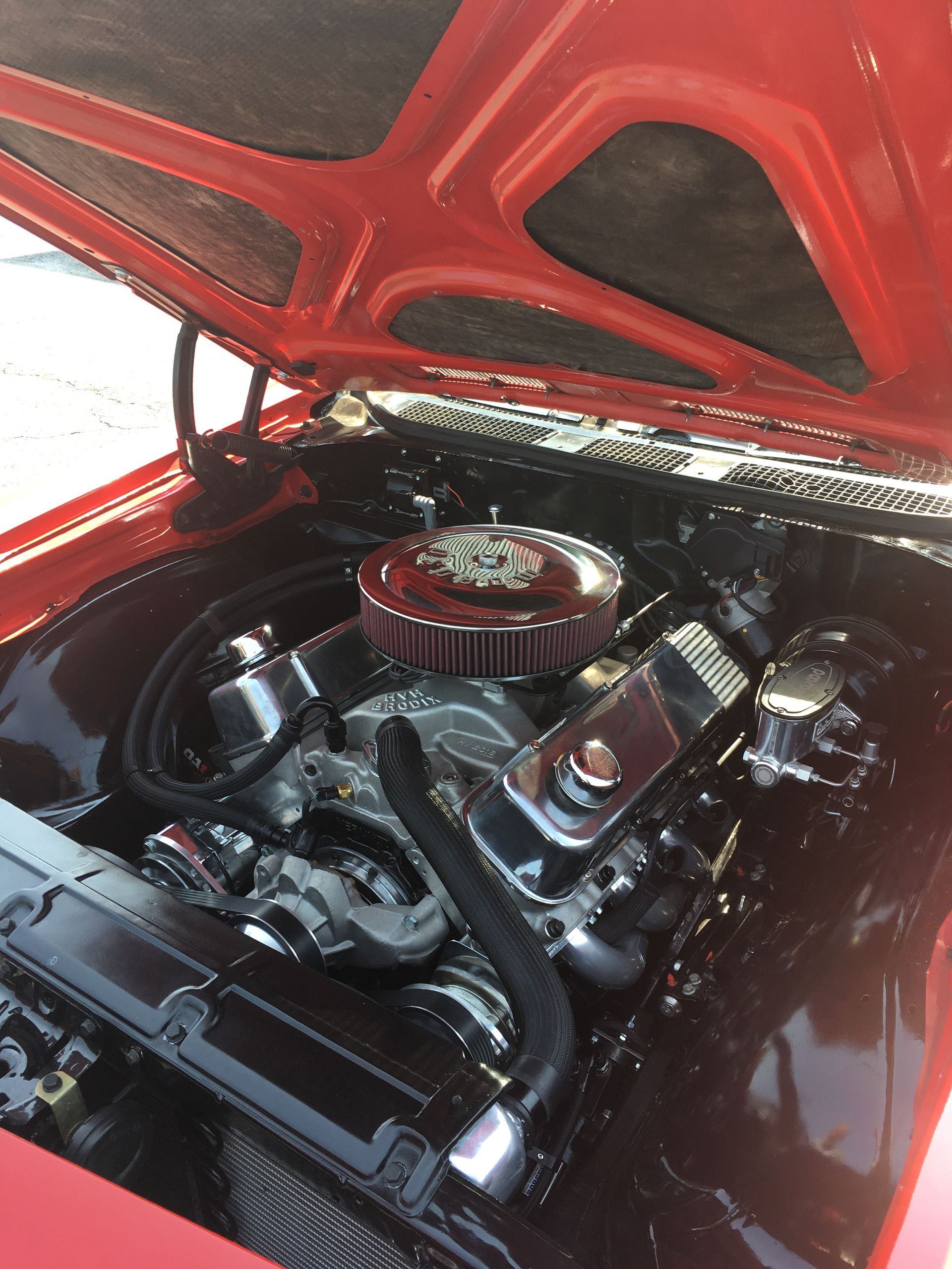 Red classic car engine bay, black engine and components, chrome accents.