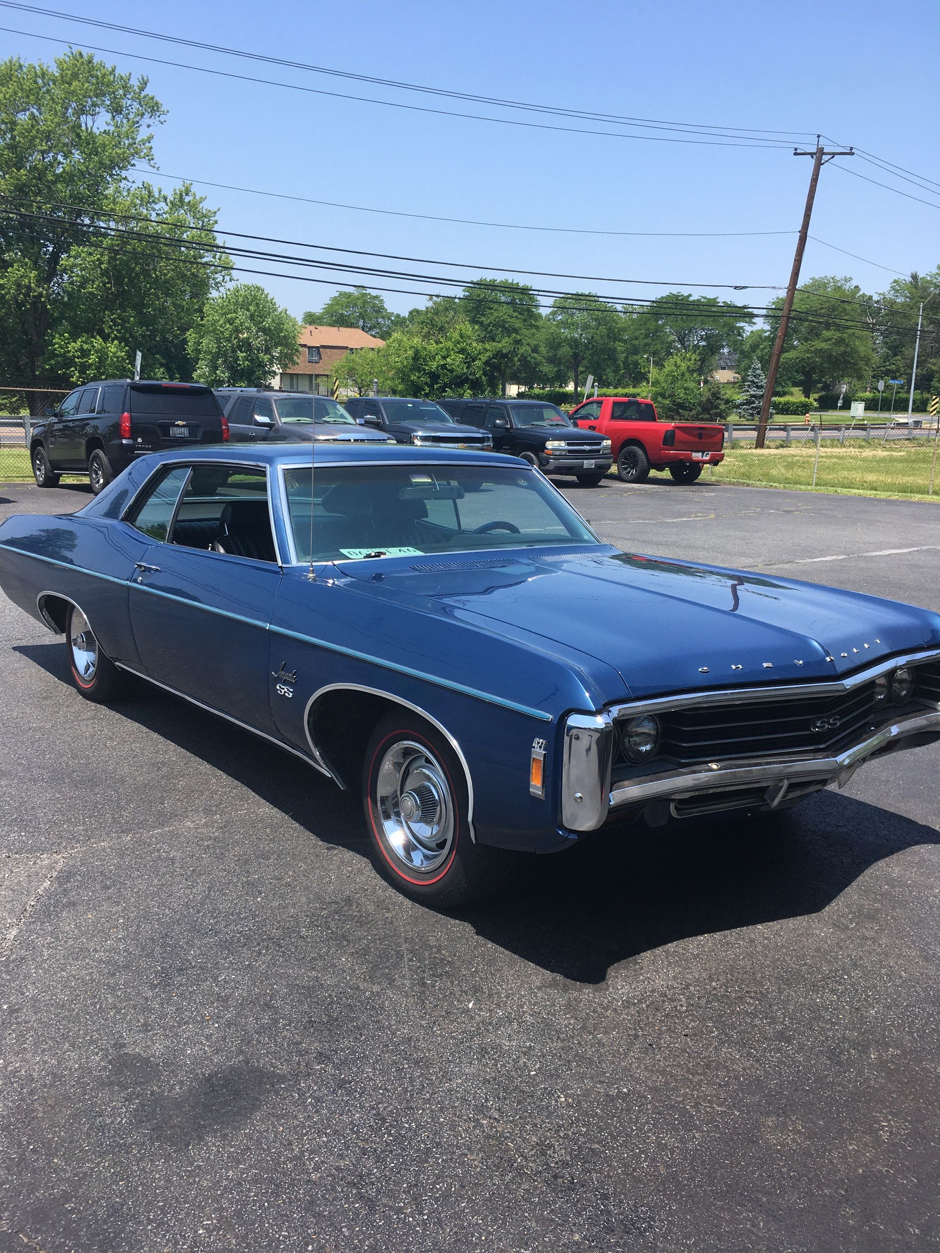 Blue 1969 Chevrolet Impala coupe parked in a lot on a sunny day.