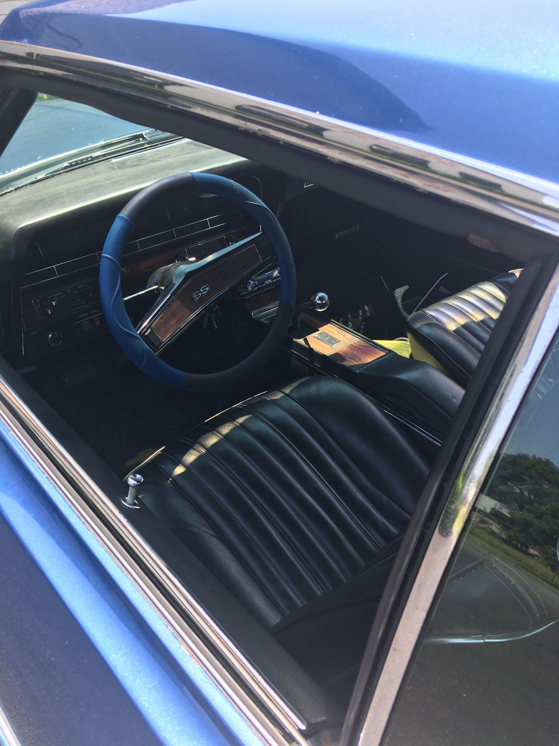 Blue car interior with a blue steering wheel, black seats, and chrome trim.