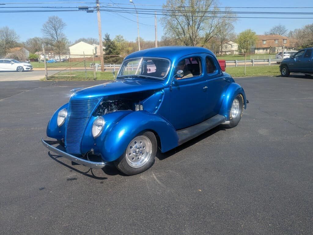 Blue classic hot rod car parked outdoors on pavement.