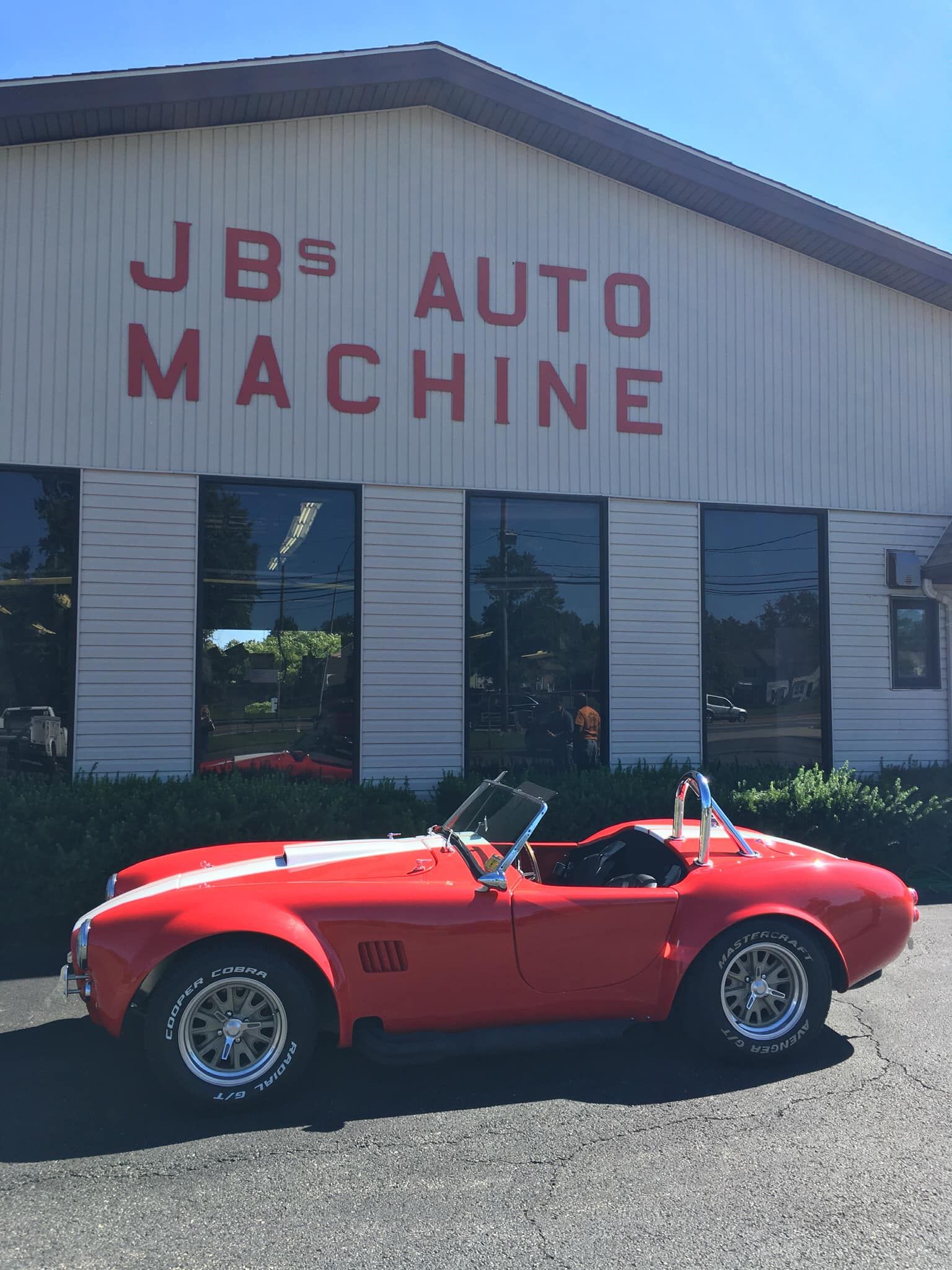 Red Shelby Cobra sports car parked in front of 