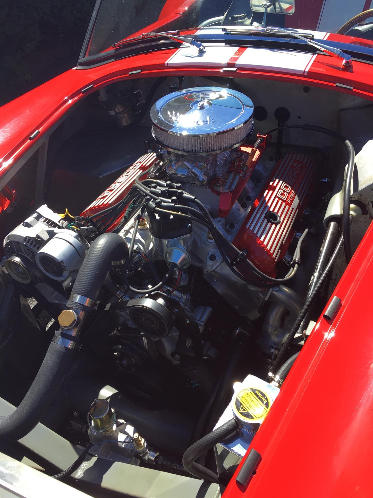 Red Cobra sports car engine compartment with chrome and red detailing.