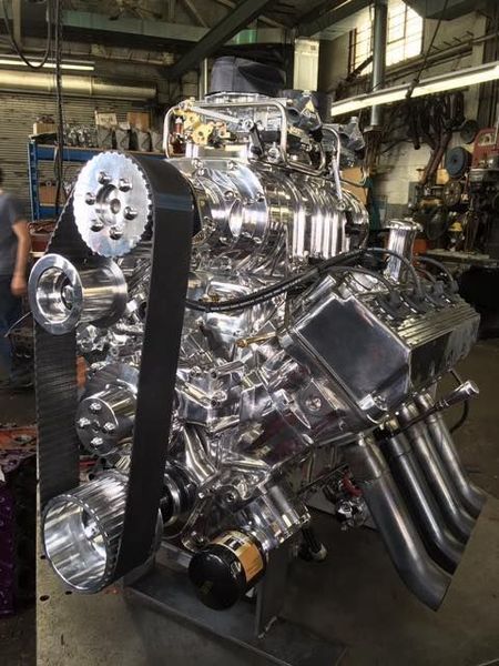 Polished, chrome-detailed engine with a black belt in a workshop setting.