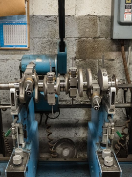 Blue industrial machine with dials and a mechanical arm in a workshop setting.