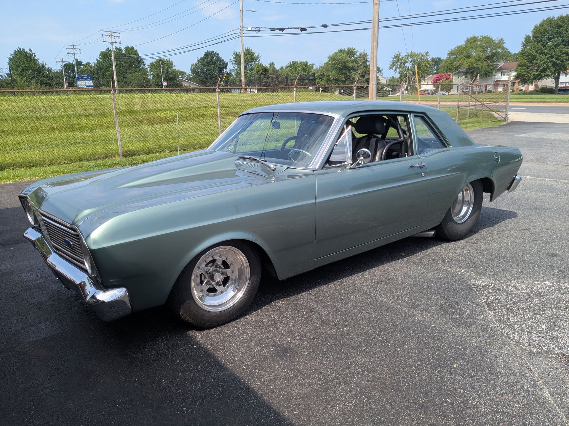 Classic gray-green muscle car parked outdoors on a sunny day.