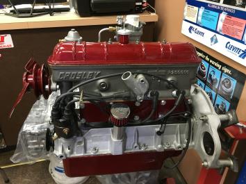 Crosley engine, red and silver, on a stand in a garage.