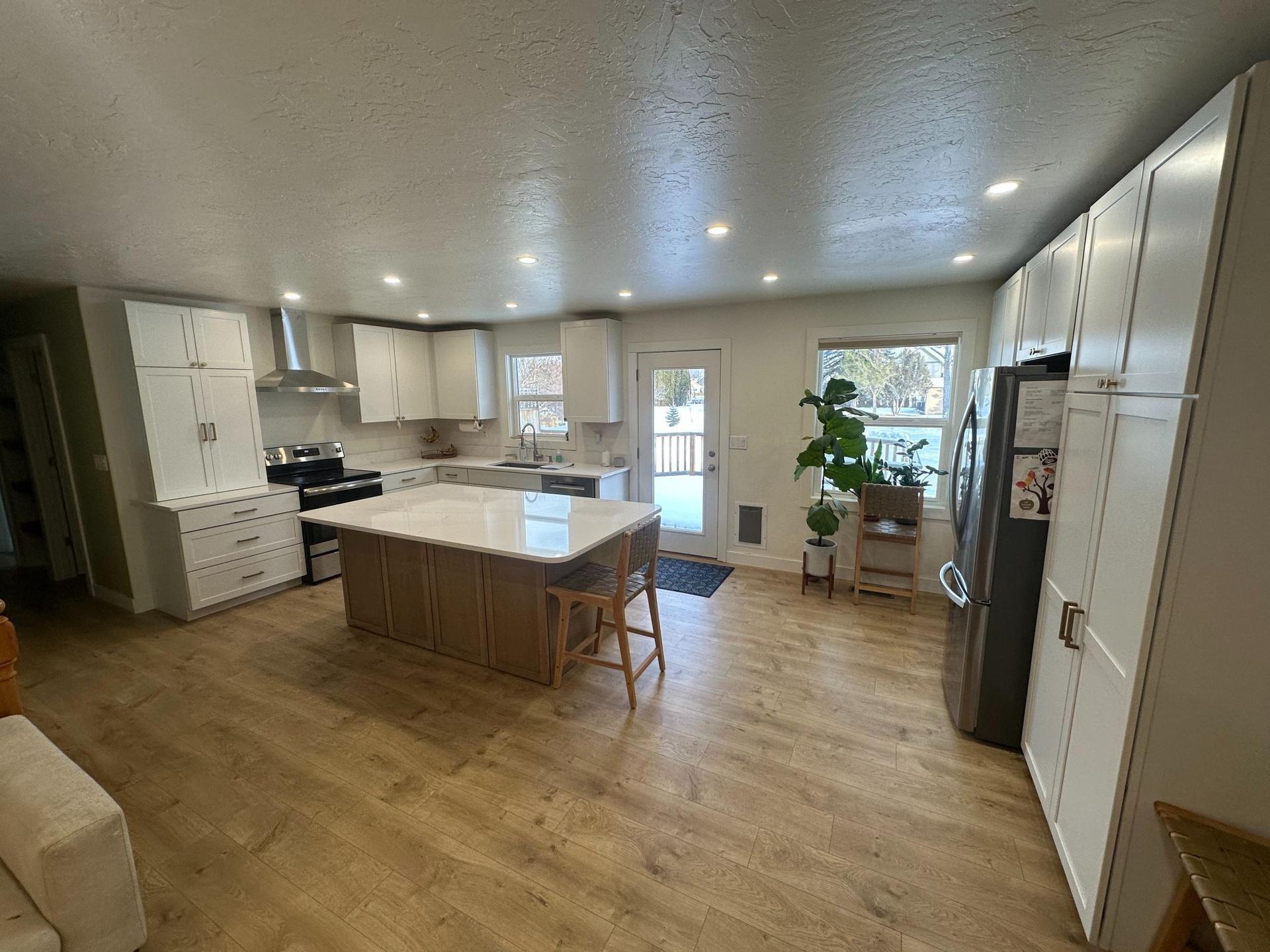 Bright, modern kitchen with white cabinets, light wood island, and stainless steel appliances.