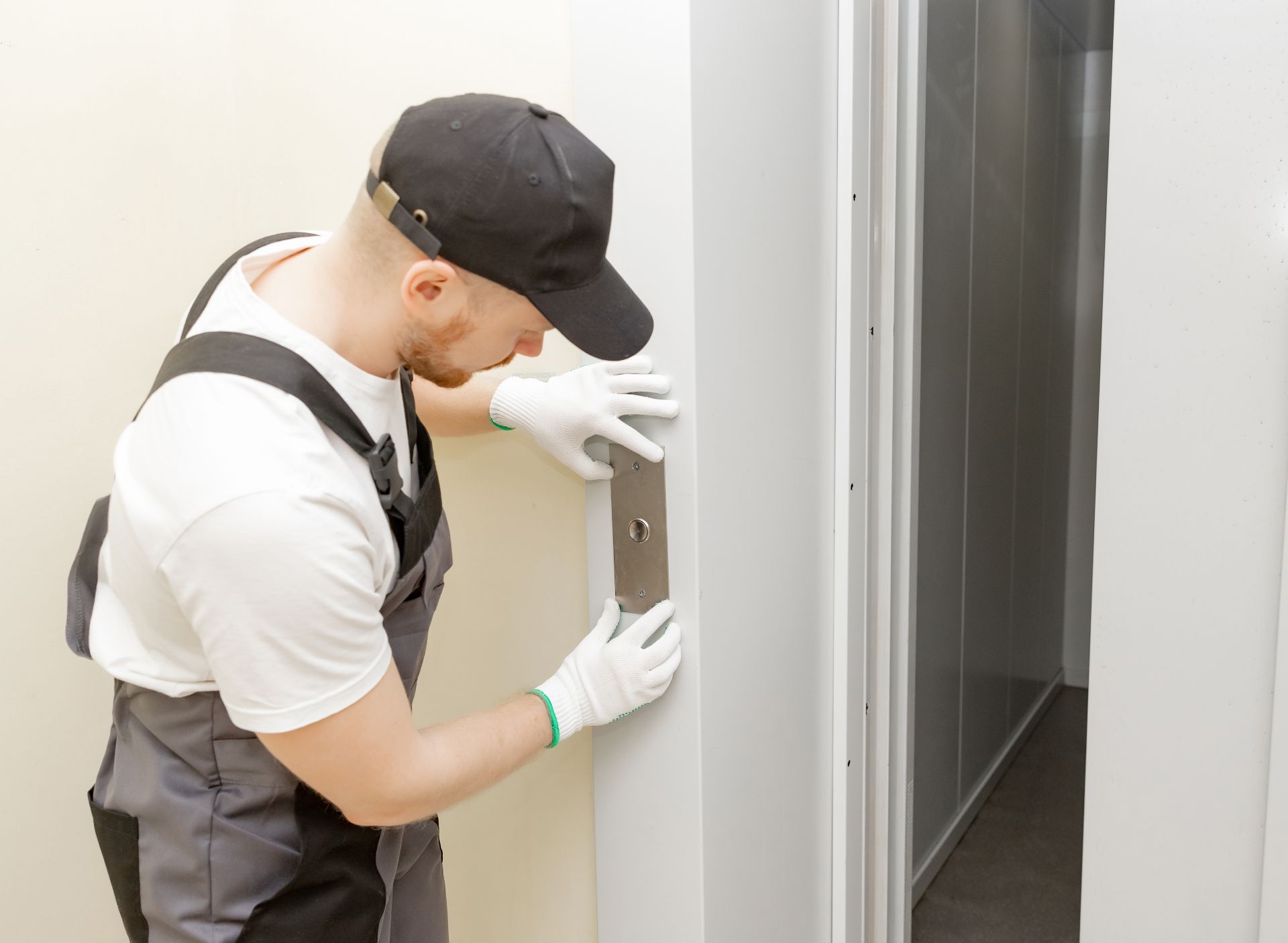 Technician in gloves inspecting a door frame beside an open doorway