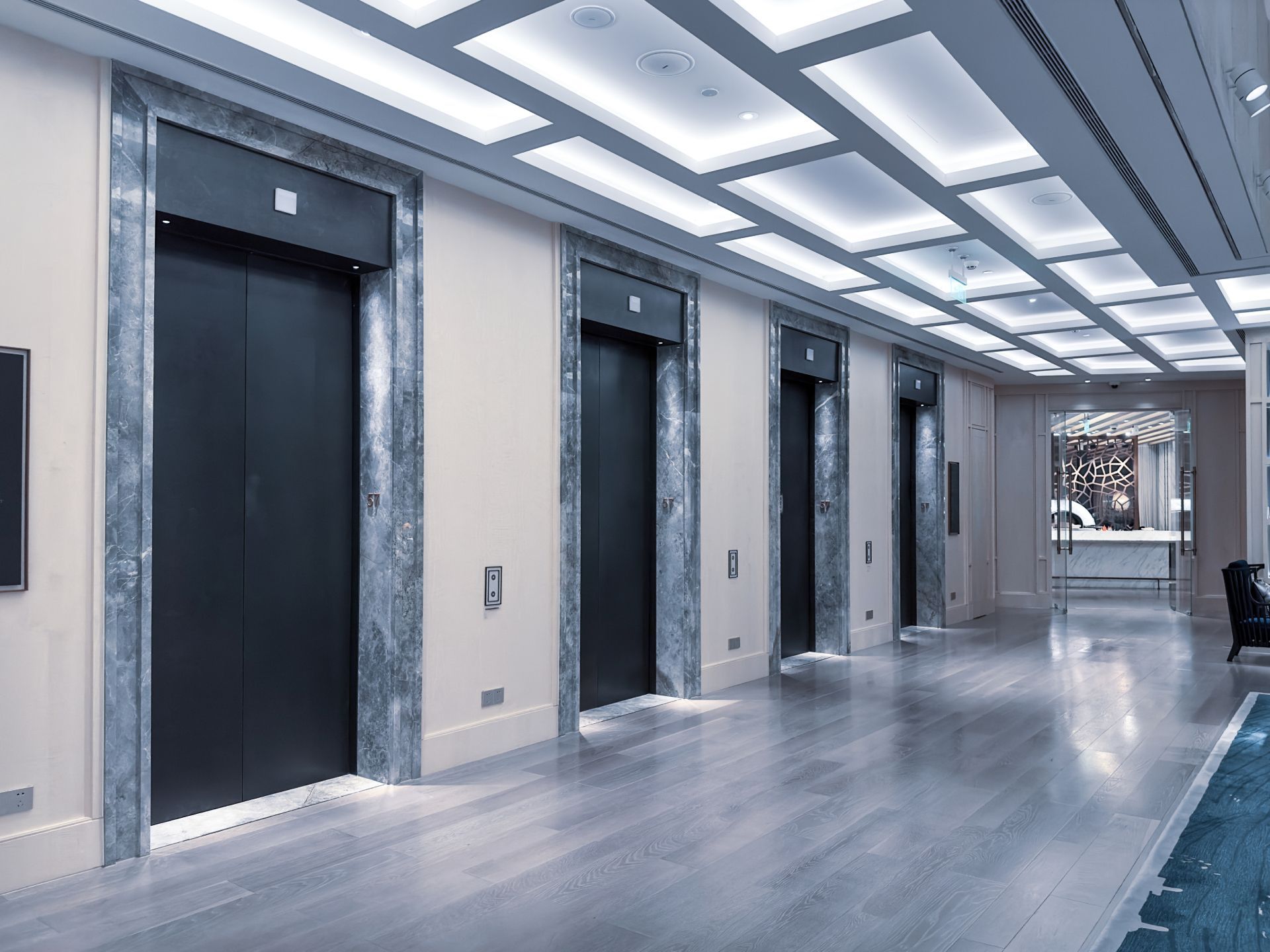 Modern lobby with elevator doors, bright ceiling lights, and polished floor